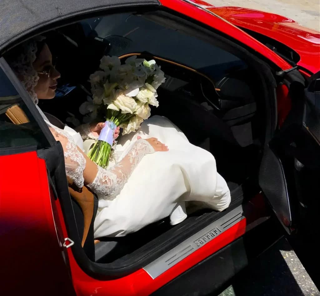 Bride holding her bouquet inside a red Ferrari