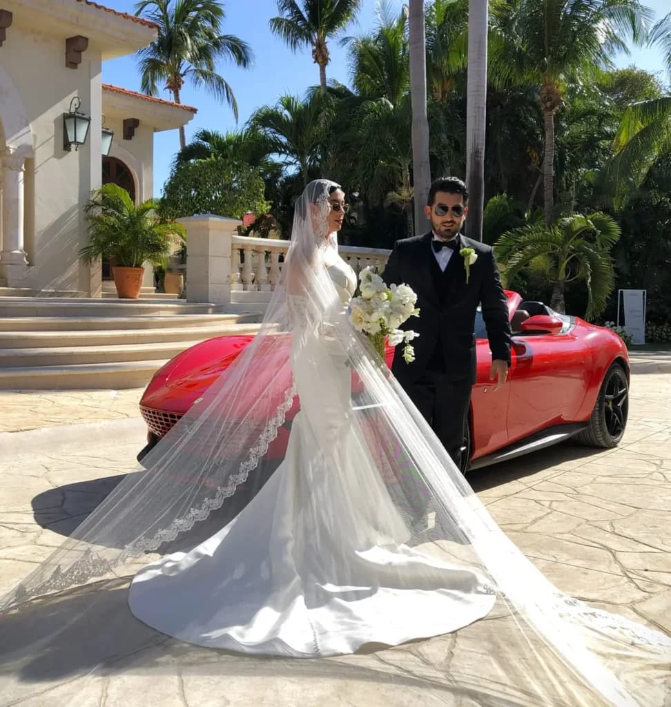Newly married couple walking beside a red Ferrari