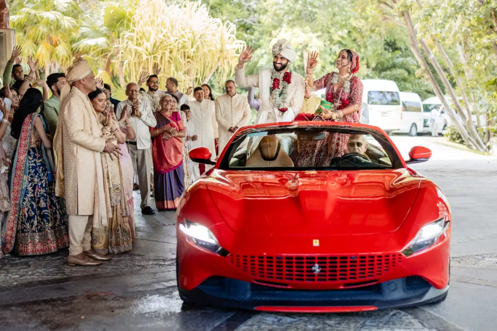 Wedding family celebrating behind a red Ferrari